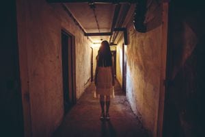 Scary girl in night gown in a dark basement hallway