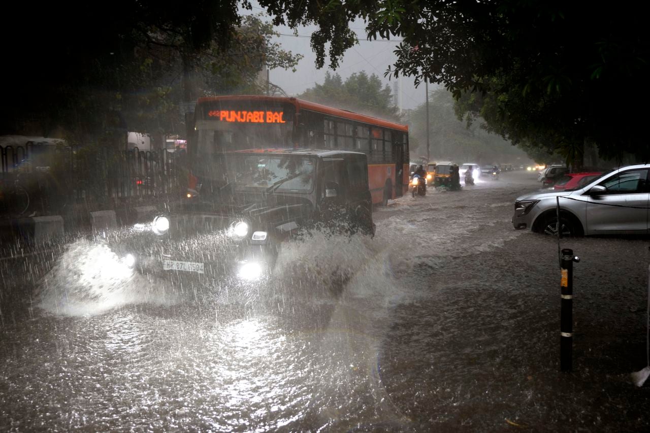 Los vehículos circulan por una calle anegada durante un fuerte aguacero en Nueva Delhi, India, el domingo 9 de julio de 2023.