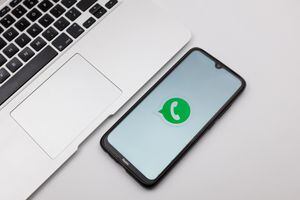 In this photo illustration a WhatsApp logo seen displayed on a smartphone screen on a desk next to a Macbook in Athens, Greece on November 14, 2022. (Photo Illustration by Nikolas Kokovlis/NurPhoto via Getty Images)