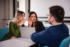 Dos mujeres de negocios chismean sobre su colega en una reunión de negocios