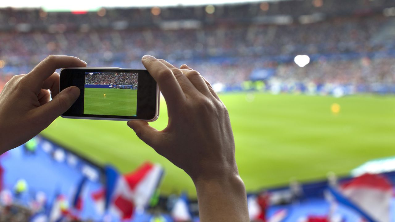 Persona graba con su celular en un estadio