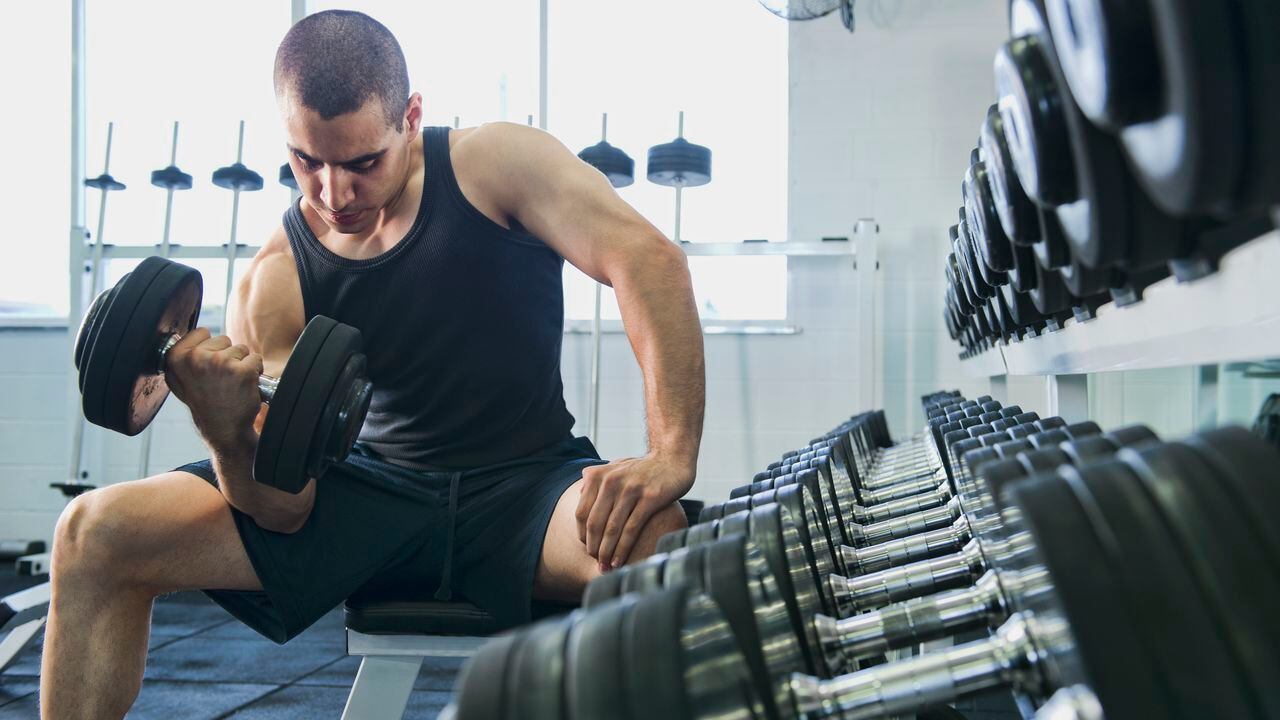 Hombre en el gimnasio realizando ejercicios para fortalecer los bíceps