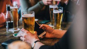 Hombre que sostiene una cerveza y un teléfono móvil, en Ámsterdam (Países Bajos)