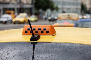 Taxi car roof with raindrops on road background, rain in city