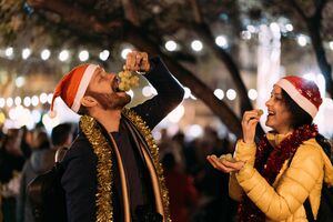 Happy couple celebrating New Year outside at night and eating grapes