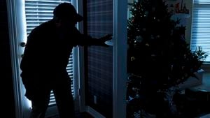 Esta foto ilustra un robo o un ladrón que irrumpe en una casa por la noche a través de una puerta trasera durante la temporada navideña. Vista desde el interior de la residencia.