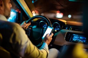 Close up of a businessman using his phone for navigation while driving his car in the evening