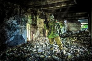 Unrecognizable soldier with a gas mask and a rifle in a warehouse (chemical and biological weapons concept).