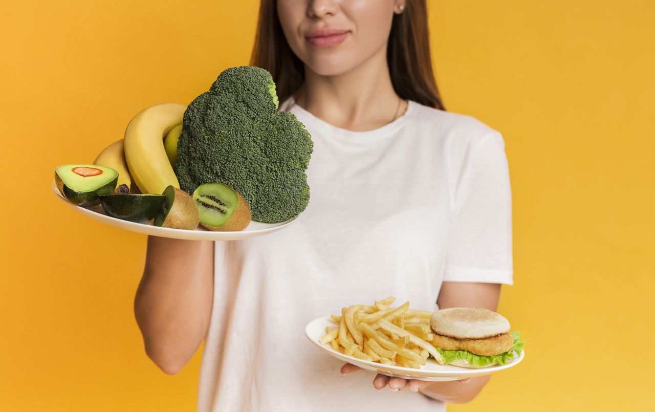 Mujer con un plato de comida saludable en una mano y en la otra un plato de comida rápida
