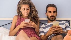 Sad couple using smartphone in bed