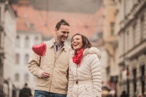 Couple in beige clothings with hearts embracing outdoors. Horizontal color image. Selective focus. Ljubljana, Slovenia.
