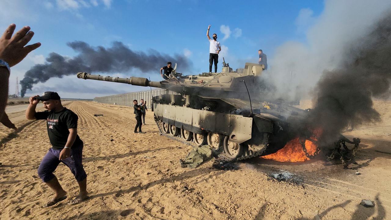 Los palestinos celebran junto a un tanque israelí destruido en la valla de la Franja de Gaza al este de Khan Younis, al sur, el sábado 7 de octubre de 2023.