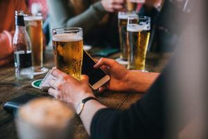 Hombre que sostiene una cerveza y un teléfono móvil, en Ámsterdam (Países Bajos)