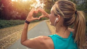 Beautiful and sporty young woman makes a heart shape finger frame after jogging outdoors. Sunset light on the vegetation.
