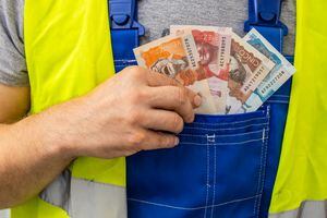 Worker counting his earnings, Colombia money, Concept of wages and labor costs in industry