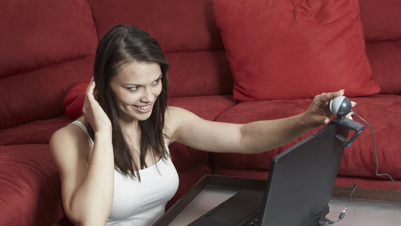 Young woman adjusting webcam on laptop
