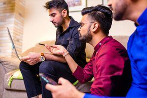 friends from india looking something interesting on laptop in livingroom.