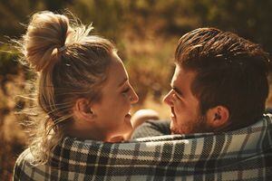 Shot of an affectionate couple wrapped in a blanket while spending time out in nature