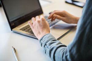 Close up of female hand using laptop on office table. Cropped shot of businesswoman working on laptop.