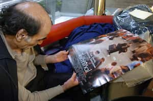 (ARCHIVOS) En esta foto de archivo tomada el 12 de agosto de 2004, Mehran Karimi Nasseri mira un póster de la película inspirada en su vida, en la terminal 1 del aeropuerto Charles De Gaulle de París. - Mehran Karimi Nasseri, un refugiado político que vivió más de 18 años en el aeropuerto Roissy-Charles de Gaulle de París e inspiró "La terminal" del director Steven Spielberg, murió, a los 77 años, en la terminal 2F del aeropuerto Roissy-Charles de Gaulle, según informó a AFP por funcionarios del aeropuerto. (Foto de STEPHANE DE SAKUTIN / AFP)