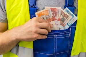 Worker counting his earnings, Colombia money, Concept of wages and labor costs in industry