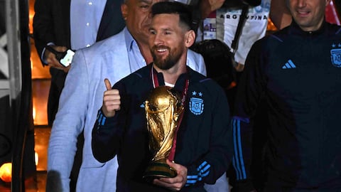Argentina's captain and forward Lionel Messi (C) holds the FIFA World Cup Trophy alongside Argentina's coach Lionel Scaloni (R) upon arrival at Ezeiza International Airport after winning the Qatar 2022 World Cup tournament in Ezeiza, Buenos Aires province, Argentina on December 20, 2022. (Photo by Luis ROBAYO / AFP)