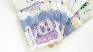 Billetes de 50 mil pesos colombianos en forma de abanico sobre fondo blanco