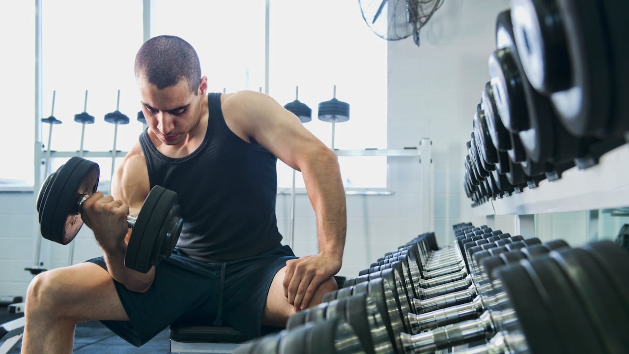 Hombre en el gimnasio realizando ejercicios para fortalecer los bíceps