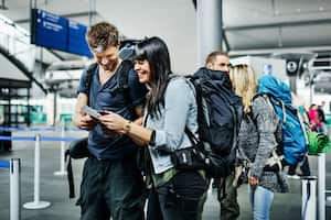 Group of young backpackers waiting at an airline checkin counter for their boarding passes