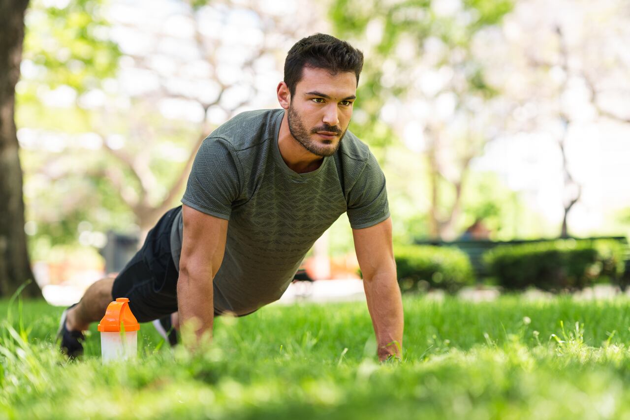 Hombre realiza flexiones en un parque