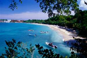 Small boats in the Northwest coast of the Dominican Republic at Playa Sosua with hotels in the background.