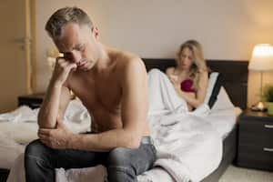 Portrait of frustrated man having a problem in bedroom and woman backgrounds