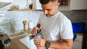 Young man making protein shake before training