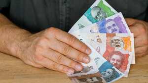 manos de hombre y mujer intercambiando billetes colombianos con fondo blanco