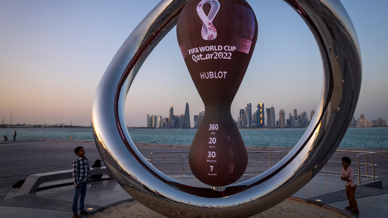 Children stand next to the official countdown clock showing remaining time until the kick-off of the World Cup 2022, in Doha, Qatar, Thursday, Nov. 25, 2021. The World Cup is due to start in November 2022. (AP Photo/Darko Bandic)
