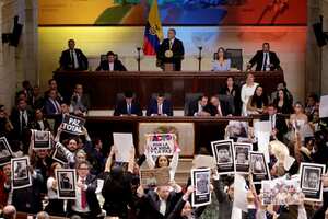 El presidente de Colombia, Iván Duque, habla durante la instalación del Congreso 2022-2026 en Bogotá, el 20 de julio de 2022. Al frente suyo, la oposición con pancartas
