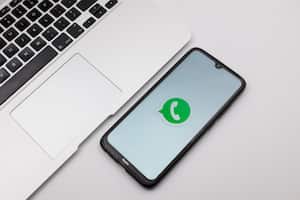 In this photo illustration a WhatsApp logo seen displayed on a smartphone screen on a desk next to a Macbook in Athens, Greece on November 14, 2022. (Photo Illustration by Nikolas Kokovlis/NurPhoto via Getty Images)
