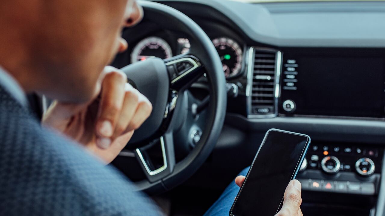 Hombre revisa su celular en el carro
