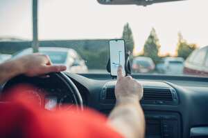 Delivery person driving a car and using GPS to determine the location of his customer