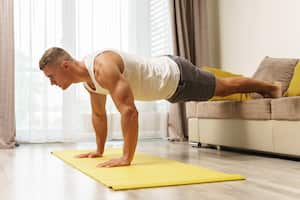 Hombre musculoso haciendo flexiones durante el entrenamiento en casa. Músculos, masa muscular, ejercicio físico, tonificar.