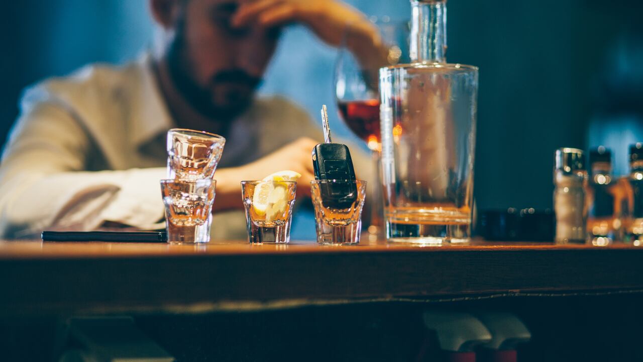 One man, sitting at the bar counter alone, he has drinking problems.