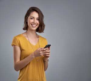 Studio portrait of an attractive young woman using her phone against a gray background