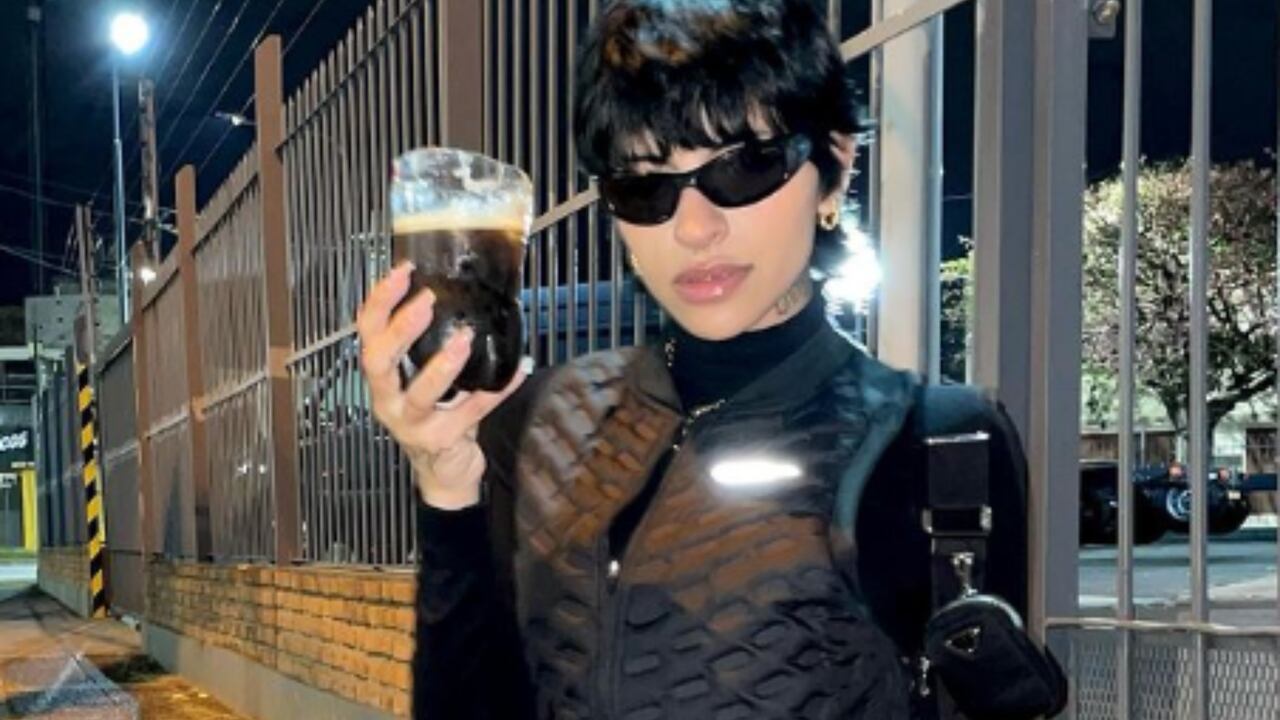 Cazzu la rapera argentina que se ha hecho con una importante carrera posa con una bebida.