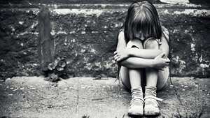 Niño deprimido sentado en la acera desgastada. Ruido fino aplicado.