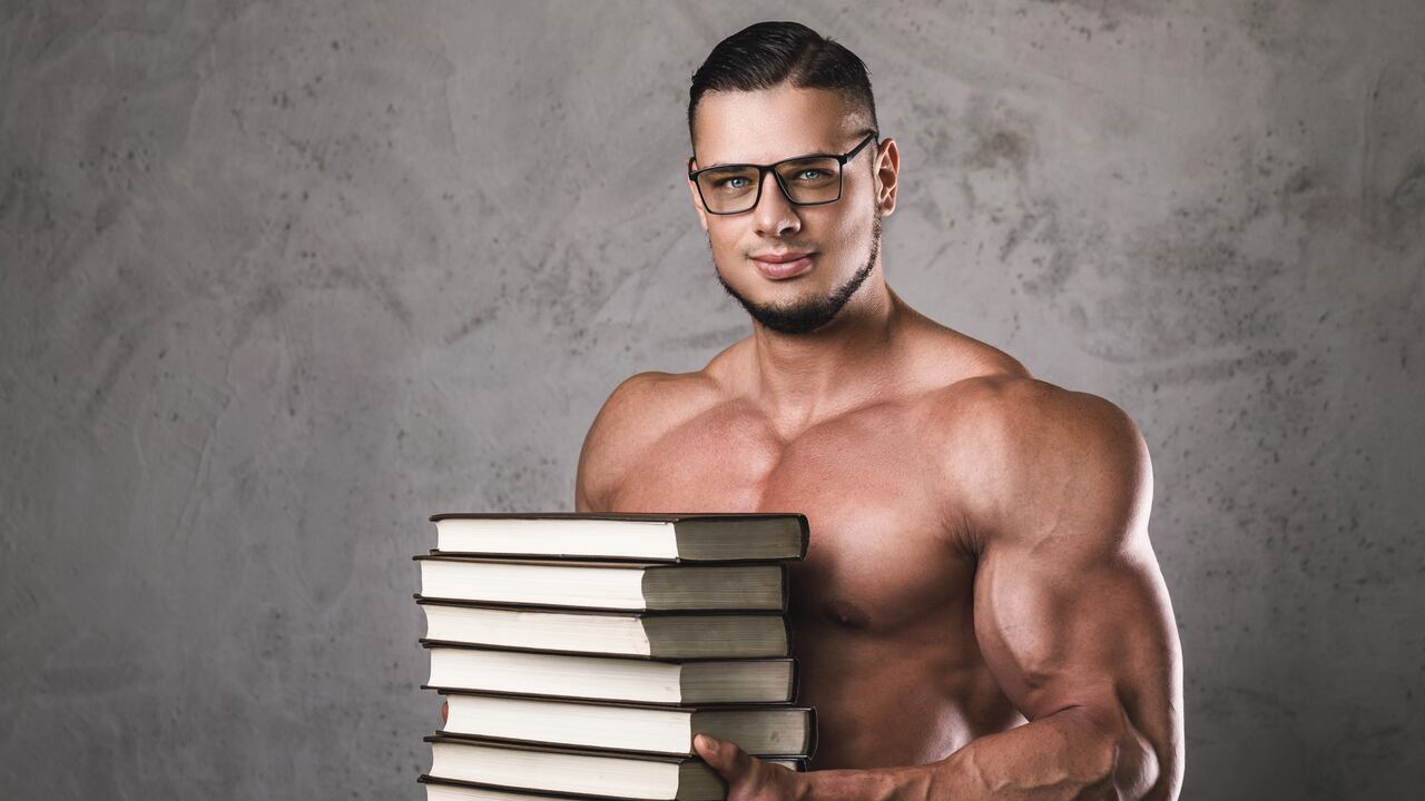Smart and muscular man with a heap of books. Concept of knowledge in bodybuilding.