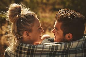 Shot of an affectionate couple wrapped in a blanket while spending time out in nature