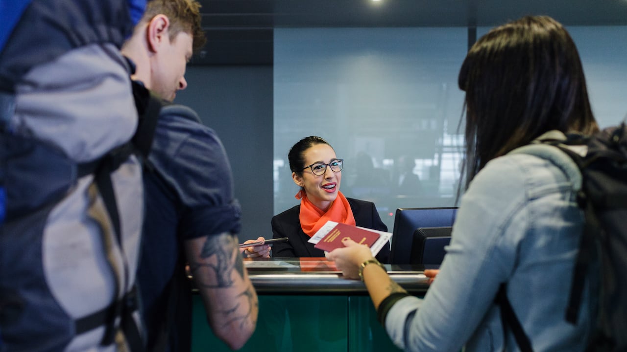 Young backpackers checking-in at airport line counter