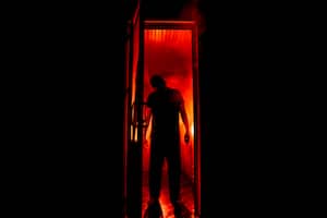 Silhouette of an unknown shadow figure on a door through a closed glass door. The silhouette of a human in front of a window at night. Scary scene halloween concept of blurred silhouette of maniac.