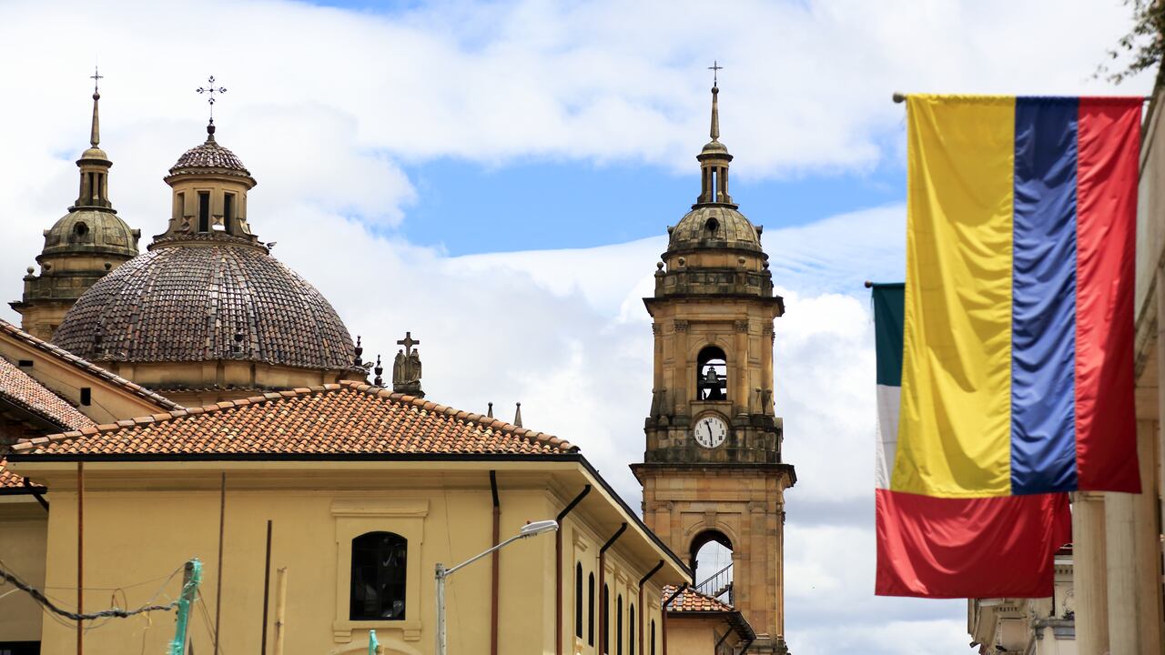 The view of the dome and bell towers of Primatial Cathedral of Bogota (Metropolitan Cathedral Basilica of the Immaculate Conception) in La Candelaria the historical center of Bogota with Colombian flag in foreground. Bogota.Colombia. 05/2017