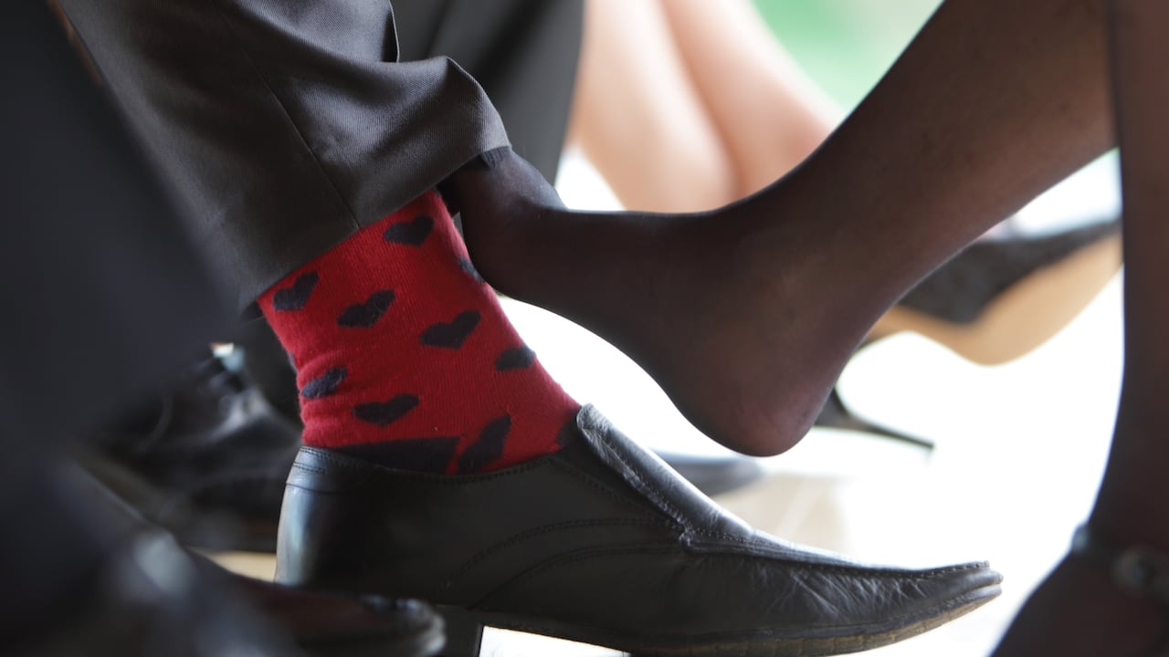 ambiente de oficina, jugando con los pies. Mujer juega con sus pies por debajo de la mesa, juego de amantes, infidelidad, infieles. Mujer rosa su pie con el pie de un hombre, coqueteo.